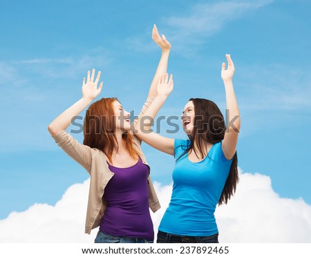 happiness, friendship and people concept - smiling teenage girls having fun over blue sky and cloud background