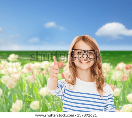education, school and vision concept - smiling cute little girl with black eyeglasses showing thumbs up gesture