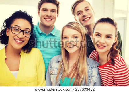 education and happiness concept - group of young smiling people at home or school