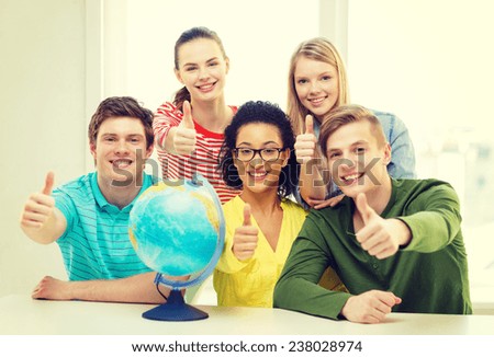 education, travel and geography concept - five smiling student with earth globe at school showing thumbs up