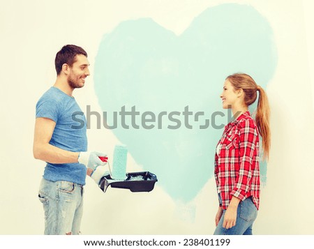 repair, building and home concept - smiling couple painting big heart on wall at home