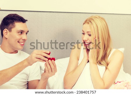 hotel, travel, relationships, holidays and happiness concept - man givnig woman little red box and ring in it