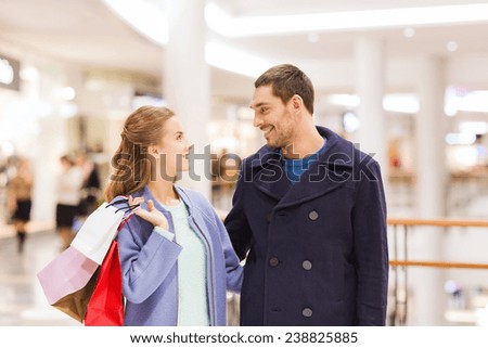 sale, consumerism and people concept - happy young couple with shopping bags talking in mall