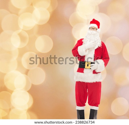 christmas, holidays and people concept - man in costume of santa claus over beige lights background