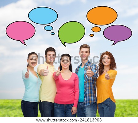 friendship, communication, gesture and people concept - group of smiling teenagers showing thumbs up over sky and grass with text bubbles