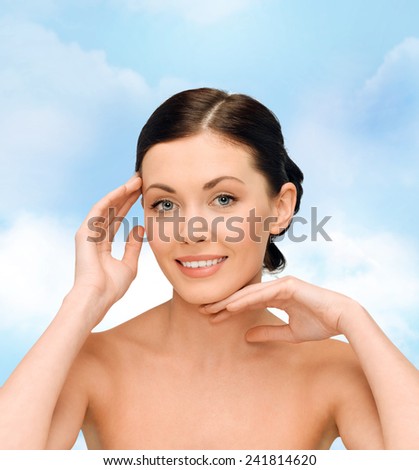 beauty, people and health concept - smiling young woman with bare shoulders over blue sky background