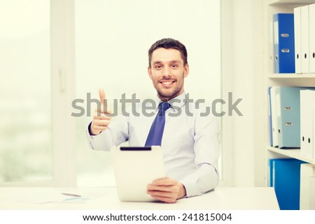 business, technology, finances and internet concept - smiling businessman with tablet pc computer and documents at office showing thumbs up