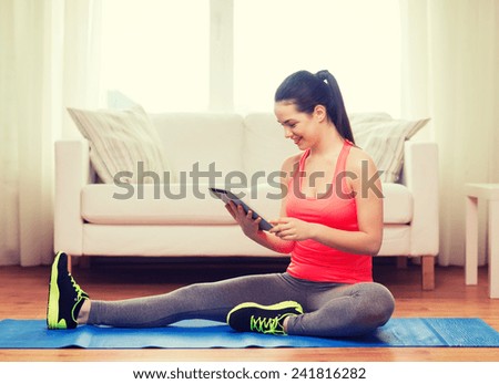 fitness, home, technology and diet concept - smiling teenage girl streching on floor with tablet pc computer at home