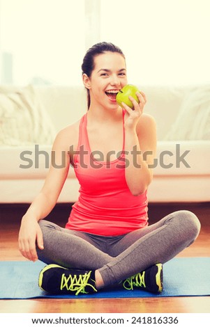 healt, dieting, home and happiness concept - smiling sporty teenage girl with green apple at home