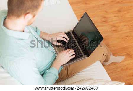 technology, leisure, advertisement and lifestyle concept - close up of man working with laptop computer and sitting on sofa at home
