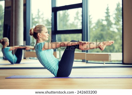 fitness, sport, training and people concept - smiling woman doing abdominal exercises on mat in gym