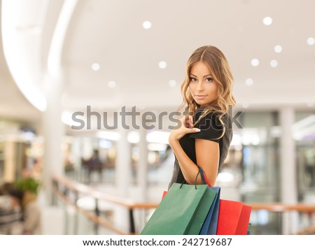 people, holidays and sale concept - young happy woman with shopping bags over mall background