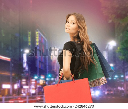 people, holidays and sale concept - young happy woman with shopping bags over night city street background