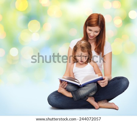 childhood, parenting and literature concept - happy mother with adorable little girl reading book over green lights background
