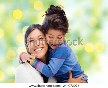 people, happiness, love, family and motherhood concept - happy mother and daughter hugging over green lights background