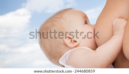 motherhood, children, people and care concept - close up of mother breast feeding adorable baby over blue sky background