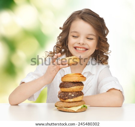 junk food, unhealthy eating, children and people concept happy smiling girl eating buns, donuts and burger over green background