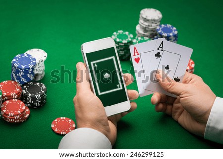 casino, online gambling, technology and people concept - close up of poker player with playing cards, smartphone and chips at green casino table