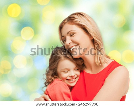 people, happiness, love, family and motherhood concept - happy mother and daughter hugging over green lights background