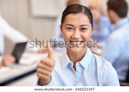 business, people, gesture and teamwork concept - smiling businesswoman showing thumbs up with group of businesspeople meeting in office