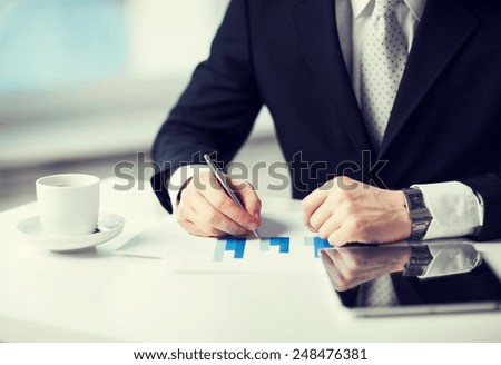 man with tablet pc, cup of coffee and graphs