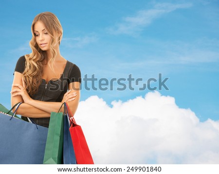 people, holidays and sale concept - young woman with shopping bags over blue sky and cloud background
