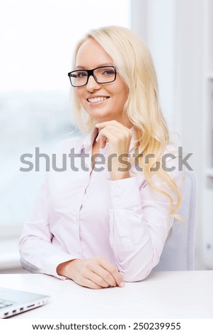 education, business and people concept - smiling businesswoman, student or secretary wearing eyeglasses sitting at table in office