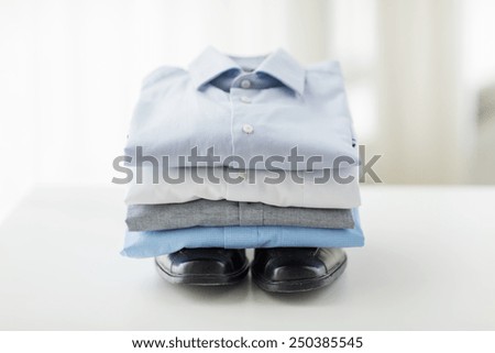 business, style, clothes, housekeeping and objects concept - close up of ironed and folded shirts and formal shoes on table at home