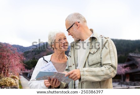 family, age, tourism, travel and people concept - senior couple with map and over asian village and mountains landscape background