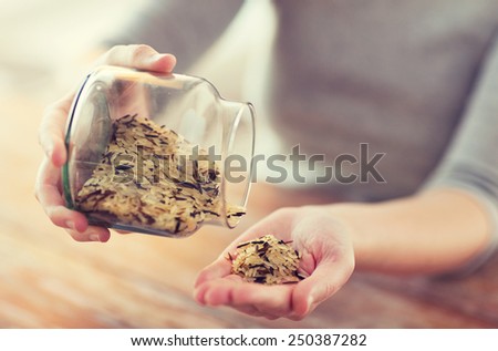 cooking and home concept - close up of female emptying jar with mixture of white and wild black rice