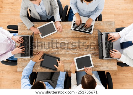 business, people and technology concept - close up of creative team with laptop and tablet pc sitting at table in office