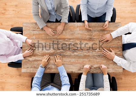 business, people and team work concept - close up of creative team sitting at table in office