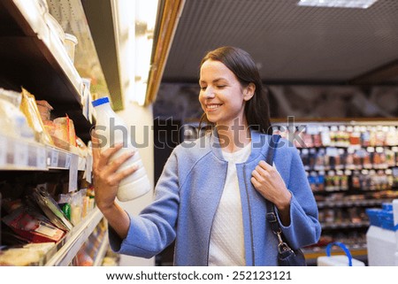 sale, shopping, consumerism and people concept - happy young woman holding milk bottle in market