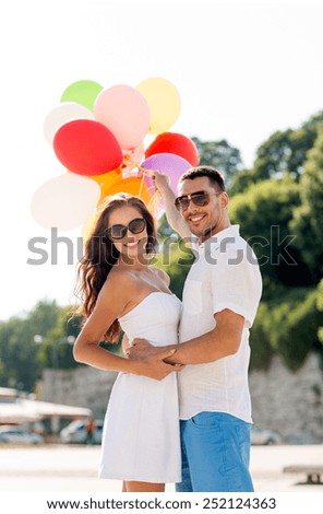 love, wedding, summer, dating and people concept - smiling couple wearing sunglasses with balloons hugging in park