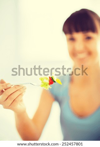 healthy food and kitchen concept - woman hand holding fork with vegetables