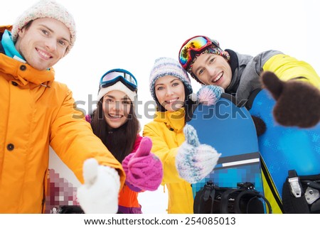winter, leisure, extreme sport, friendship and people concept - happy friends with snowboards showing thumbs up