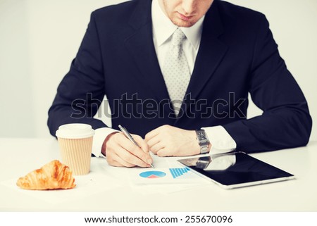 man with tablet pc and cup of coffee writing something