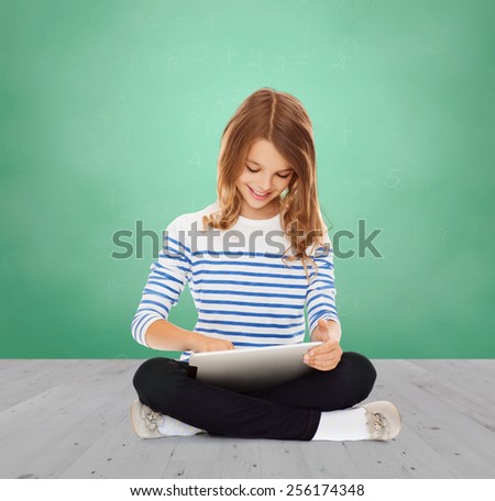 education, school, technology, childhood and people concept - happy little student girl with tablet pc over green chalk board background