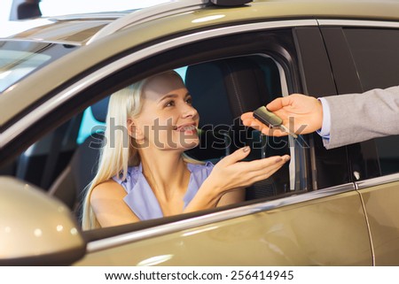 auto business, car sale, consumerism and people concept - happy woman taking car key from dealer in auto show or salon