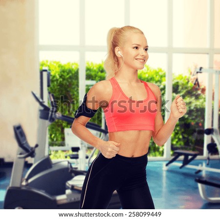 sport, exercise, technology, internet and healthcare - smiling sporty woman running and listening to music from smartphone