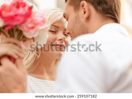 summer holidays, love, relationship and dating concept - couple with bouquet of flowers in the city