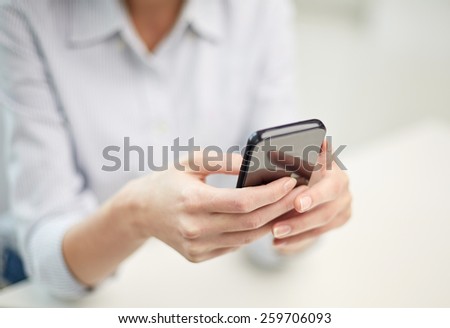 business, technology and people concept - close up of woman hands texting message on smartphone at office