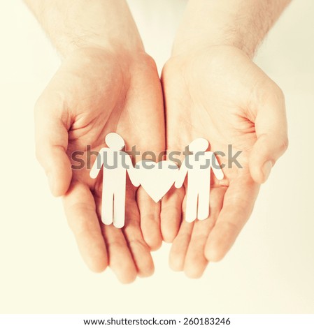 mans hands showing two paper men with heart shape