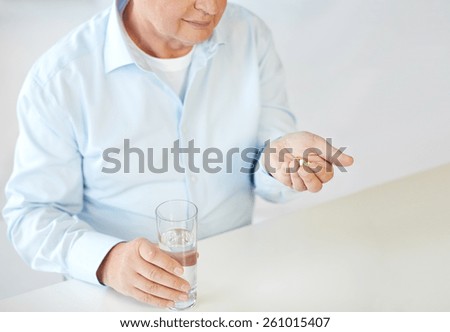 oldness, medicine, health care and people concept - close up of old man with pills and water glass
