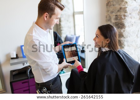 beauty, technology and people concept - happy young woman and stylist with tablet pc computer choosing hair color at salon