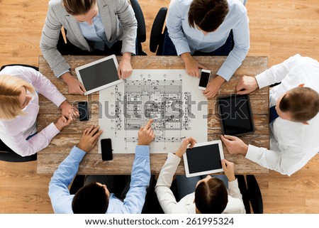 business, people, architecture and team work concept - close up of architects team with blueprint, smartphones and tablet pc computers sitting at table in office
