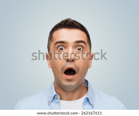 fear, emotions, horror and people concept - scared man with big eyes and open mouth shouting over gray background