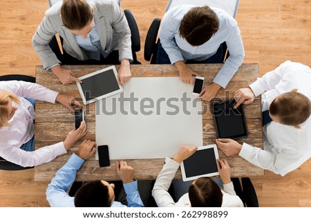 business, people, technology and team work concept - close up of creative team with, blank paper smartphones and tablet pc computers sitting at table in office