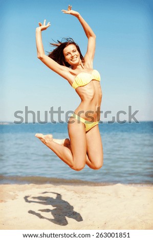 summer holidays and vacation concept - beautiful woman in bikini jumping on the beach