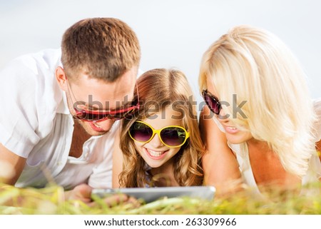 summer holidays, children and people concept - happy family with tablet pc, blue sky and green grass taking picture